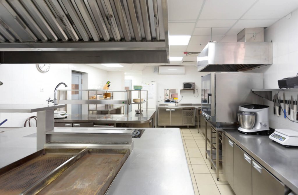 commercial kitchen with prep area, grill, hood, mixer